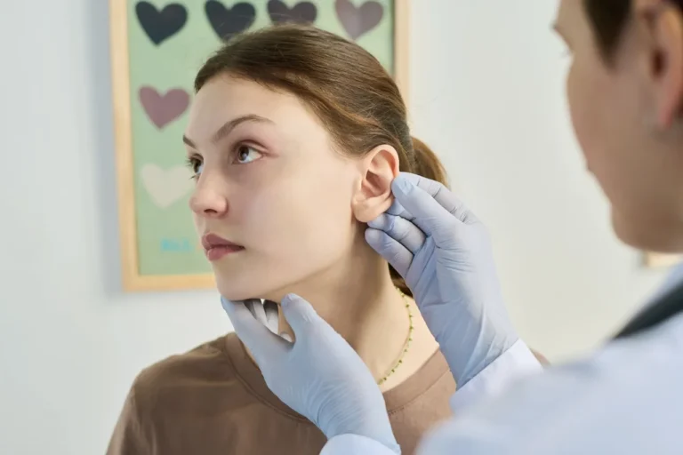 surgeon examines female patient's ear