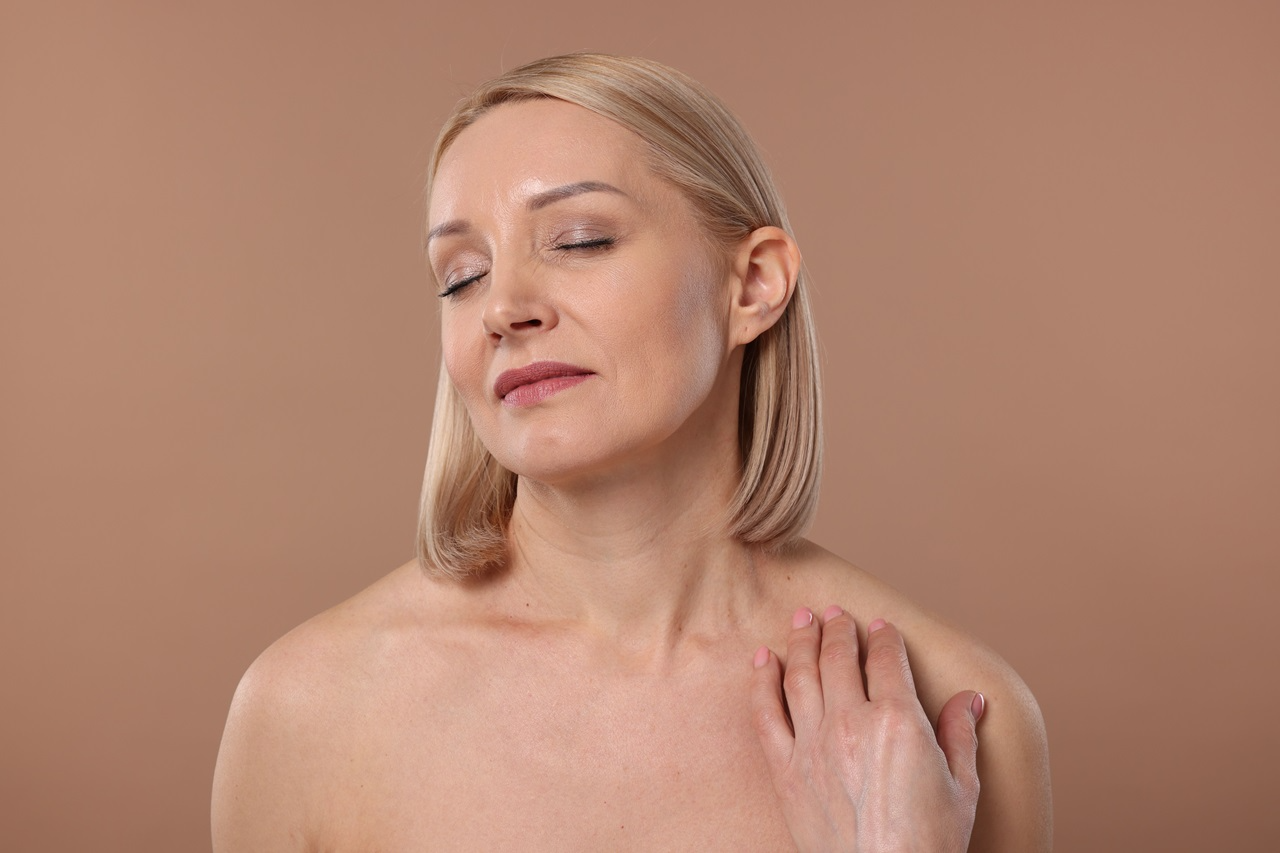 elegant looking blonde woman gently touching her shoulder